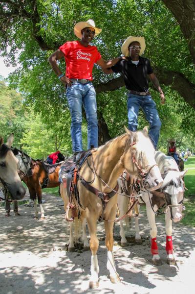 Chicago's Black Cowboys - Two cowboys show off their skills by standing on their horses while they wait for everyone to...