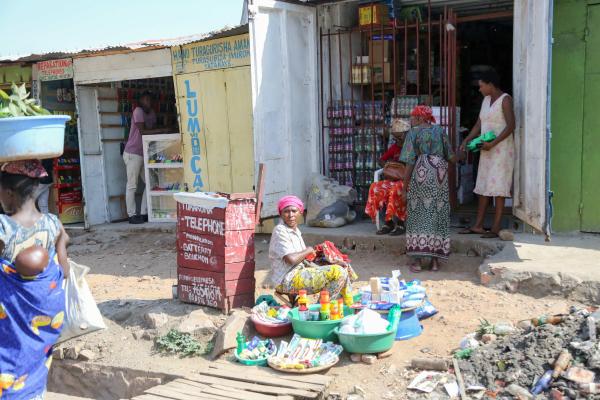 Bujumbura - City in the Heart of Africa - A woman sets with some items to sell outside of a shop in the Kamenge neighborhood. Men earn up...