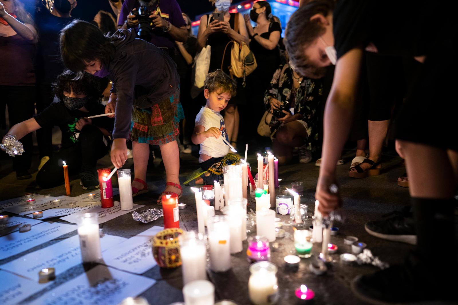 Overview - A child lights the candle of a makeshift altar in...