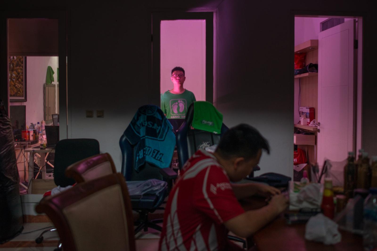 Virtual Insanity: Inside The Life of Pro-Gamers - Hartanto Tjia stands behind a window and a teammate at training bootcamp facilitated by the...