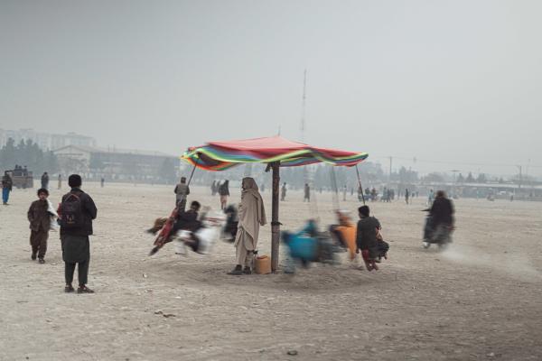 Contrasting Childhoods Joyful Play vs Hardship - Children are playing on a very old carousel. &nbsp; Kabul, Afghanistan  