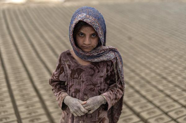 Contrasting Childhoods Joyful Play vs Hardship - A portrait of a working child who is stacking more than 500 bricks in a clay kiln