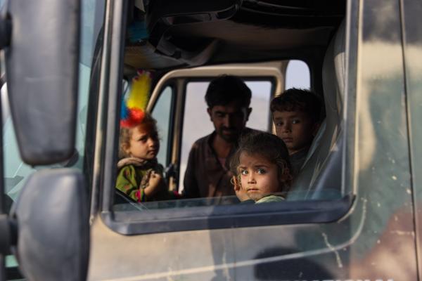 Contrasting Childhoods Joyful Play vs Hardship - The gaze of a 5-year-old girl peering from the window of her father&rsquo;s truck, recently...