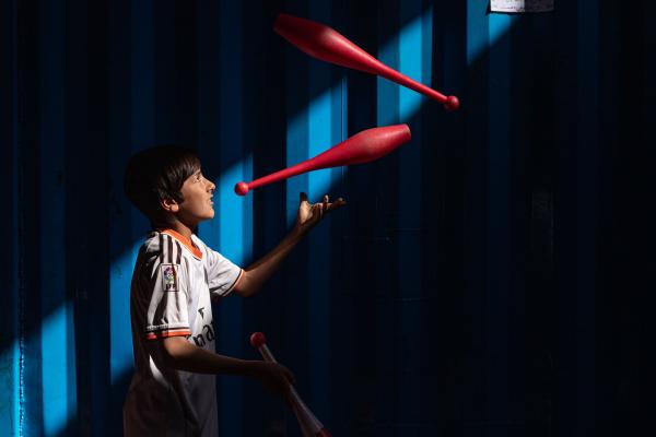 Contrasting Childhoods Joyful Play vs Hardship - A child performing tricks at the Herat Circus.