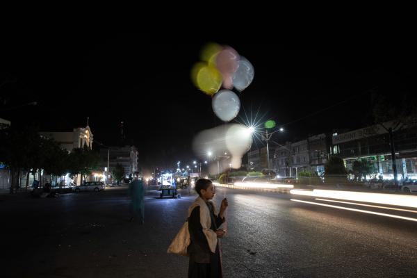 Contrasting Childhoods Joyful Play vs Hardship - A balloon seller child during the festive nights of Eid. &nbsp; Herat, Afghanistan  