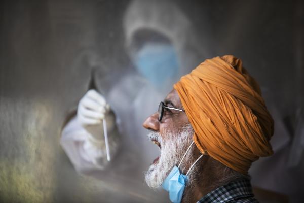 India's Covid-19 pandemic - A health official collects a swab sample from a man to...