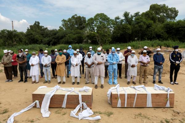 Image from India's Covid-19 pandemic - Relatives, volunteers and graveyard workers offer a...