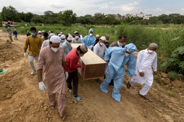 Image from India's Covid-19 pandemic - Relatives and graveyard workers carry the coffin of a...