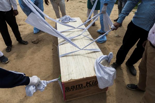 Image from India's Covid-19 pandemic - Relatives, graveyard workers and volunteers prepare to...