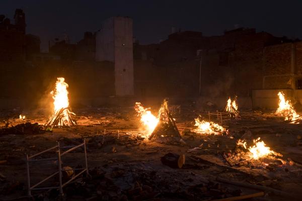 Image from India's Covid-19 pandemic - Funeral pyres of COVID-19 victims burn at an open ground...