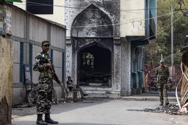 News Coverage - Security personnel stand guard outside a burnt-out mosque...