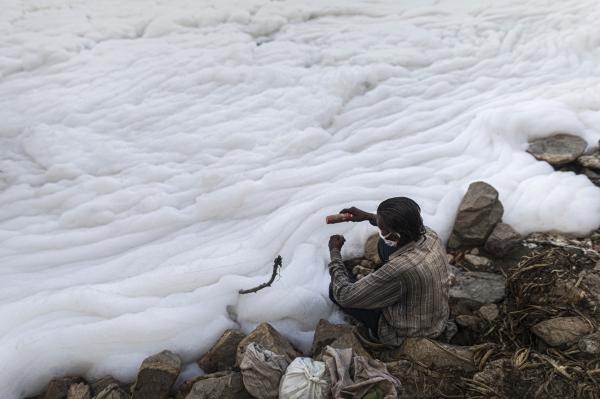 Image from News Coverage - A fisherman pulls a fishing line amidst foam along the...