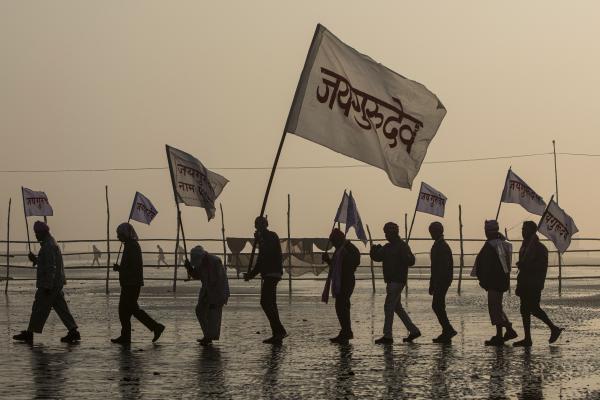 Image from Religion and Festivals - Followers of a Hindu Baba hold flags along a beach during...