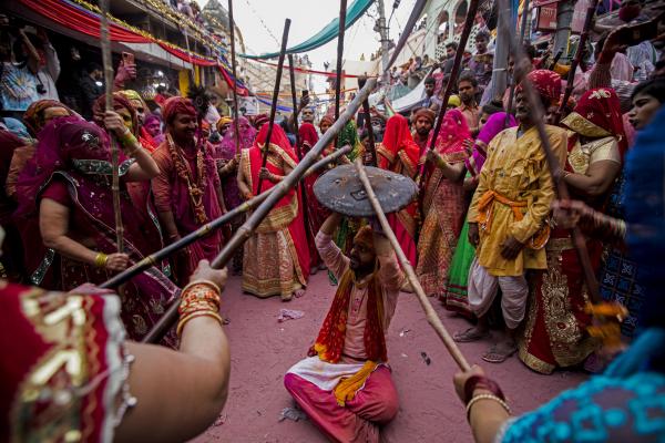 Religion and Festivals - Hindu women beat a man with sticks as they traditionally...