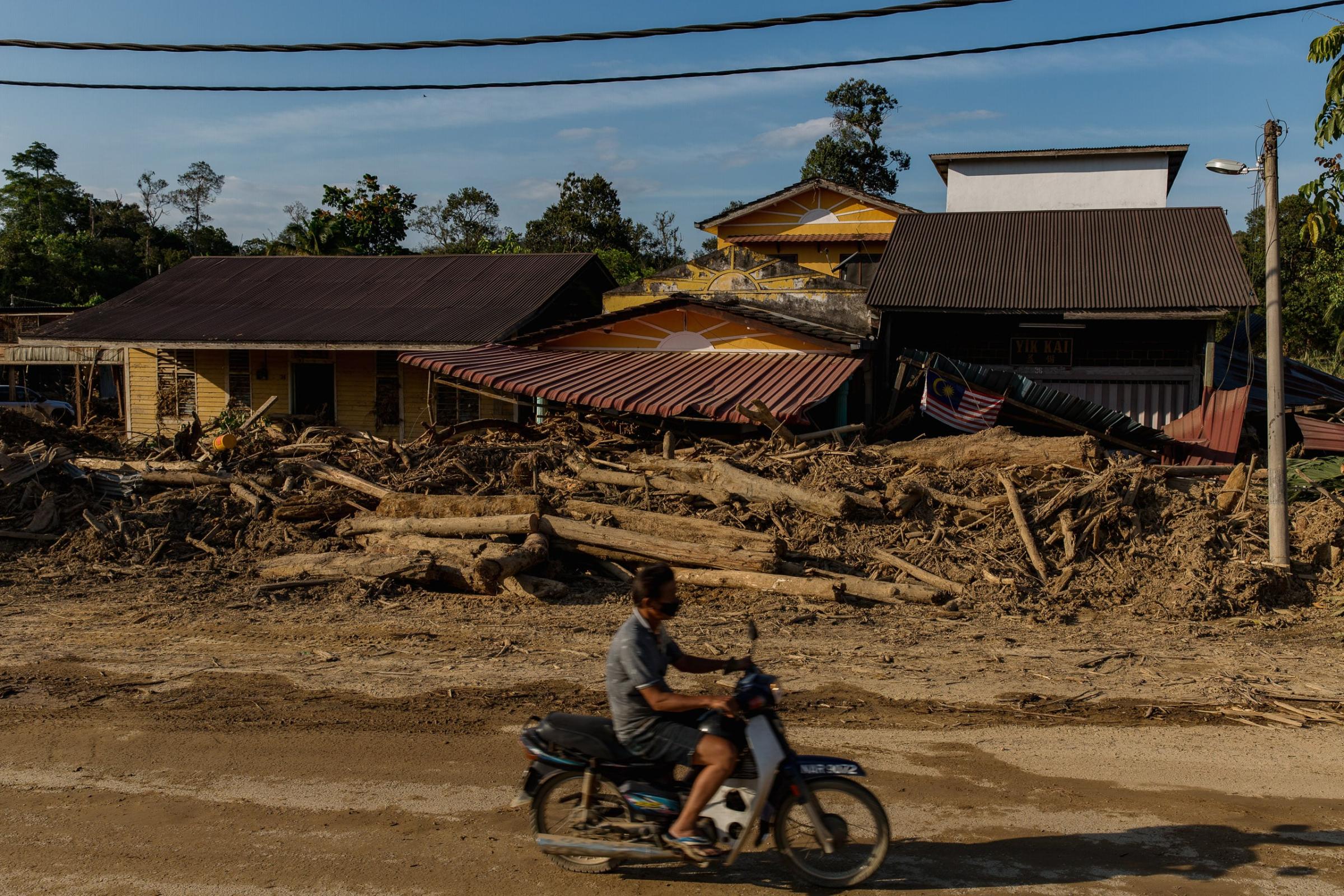 Bah: 2021 Big Flood - A motorcycle passing through a damaged house in Kampung...