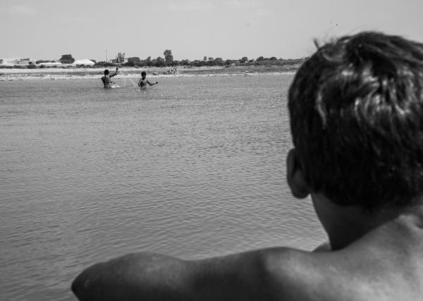 Karachi's Malir River Guardians: Defending Land, Culture, and Ecology -       A son is waiting by the riverside as his father and brother collect a fishing net during...