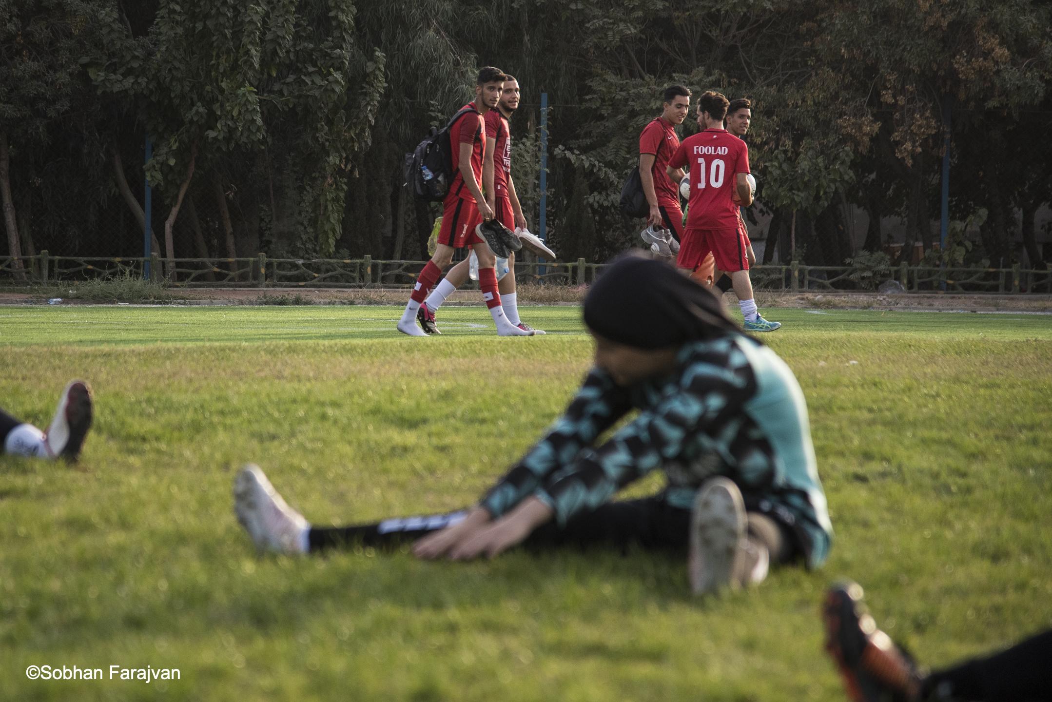 Iranian women's soccer academy - A group of boy players looks at girl player on the soccer...