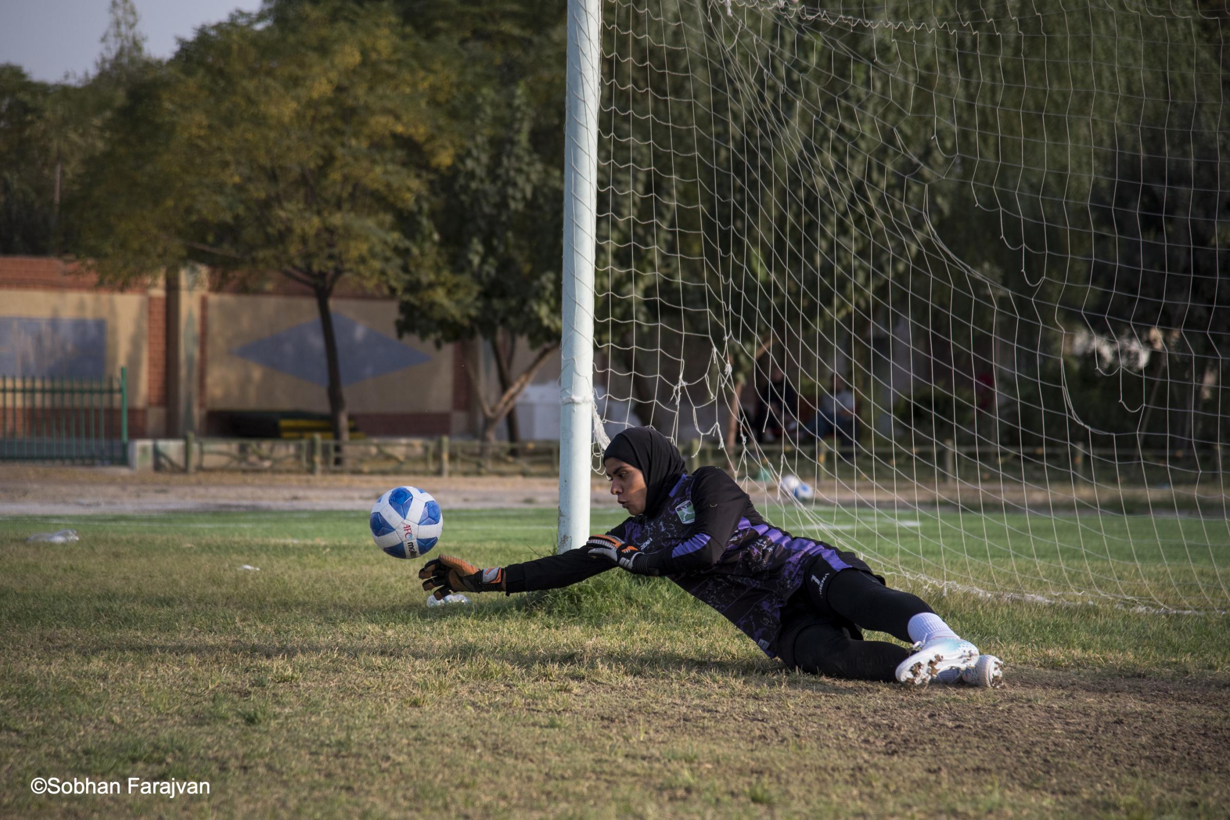 Iranian women's soccer academy (2022) - An Iranian girl goalkeeper reaching to block an attempted...