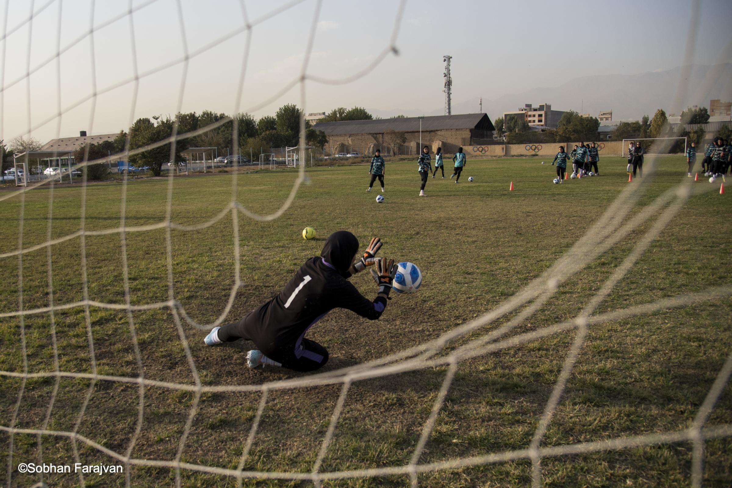 Iranian women's soccer academy (2022) - An Iranian girl goalkeeper reaching to block an attempted...