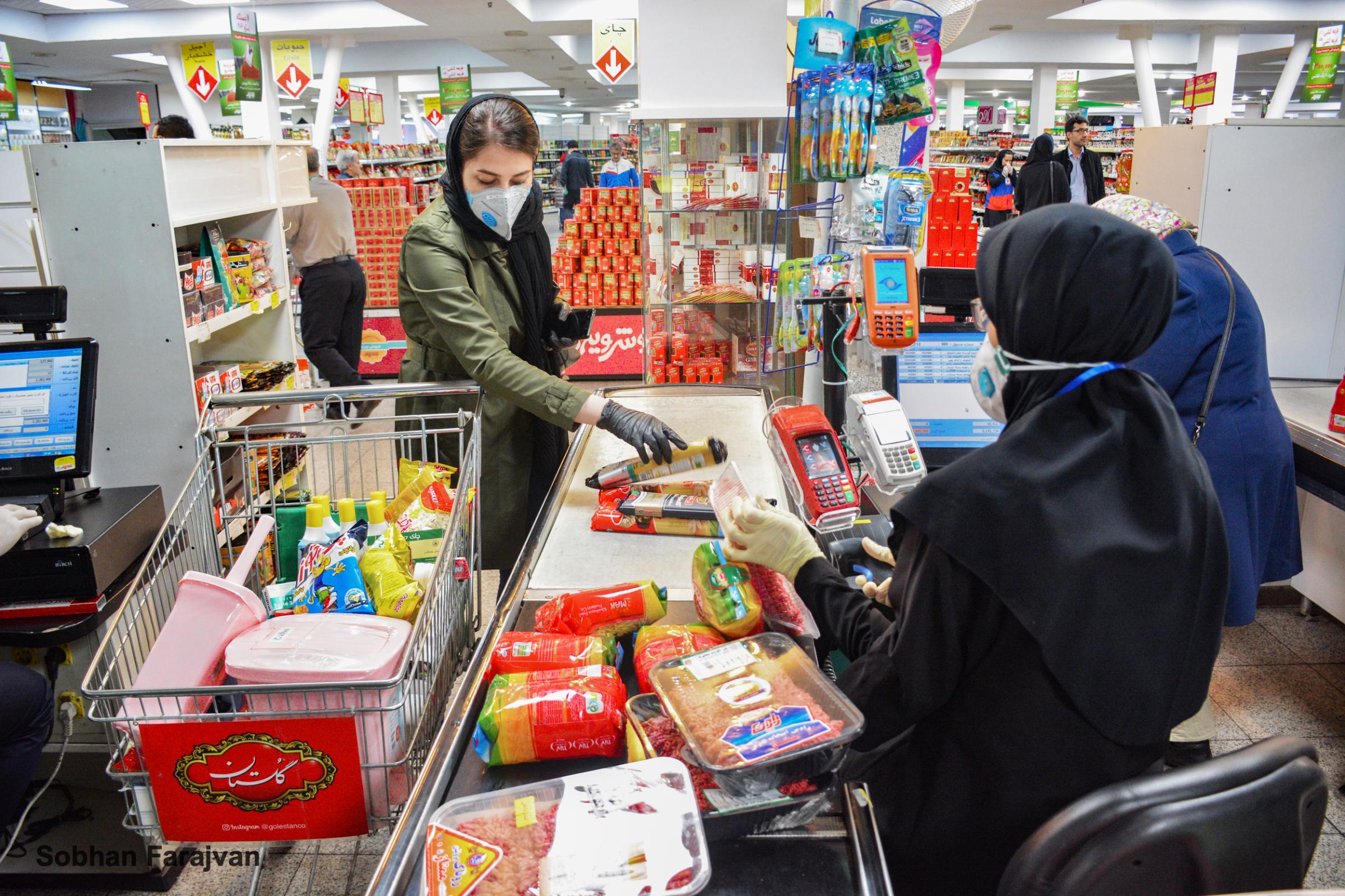 COVID-19 pandemic in Iran (2020-2022) - A woman wears a protective mask and gloves while shopping...
