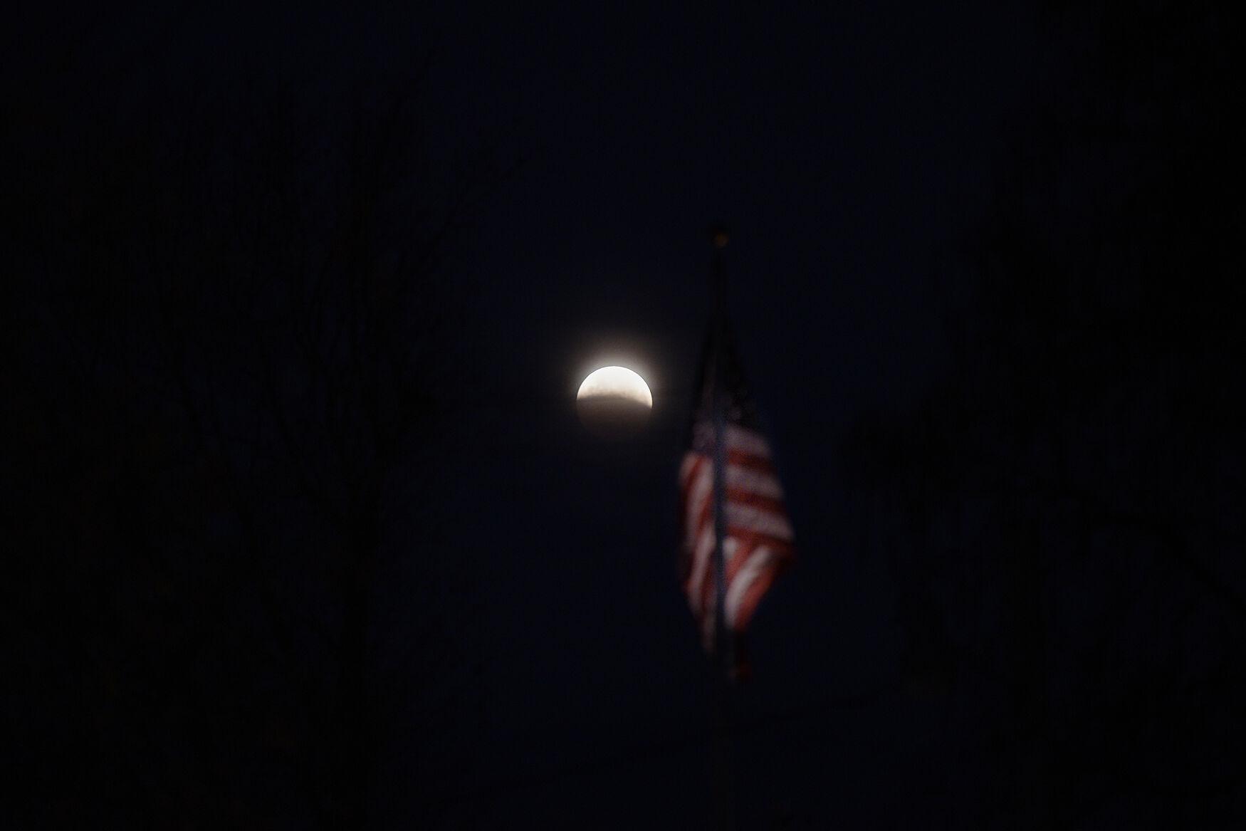 Election Day at the edge of the county - The lunar eclipse sets over an American flag on Tuesday,...