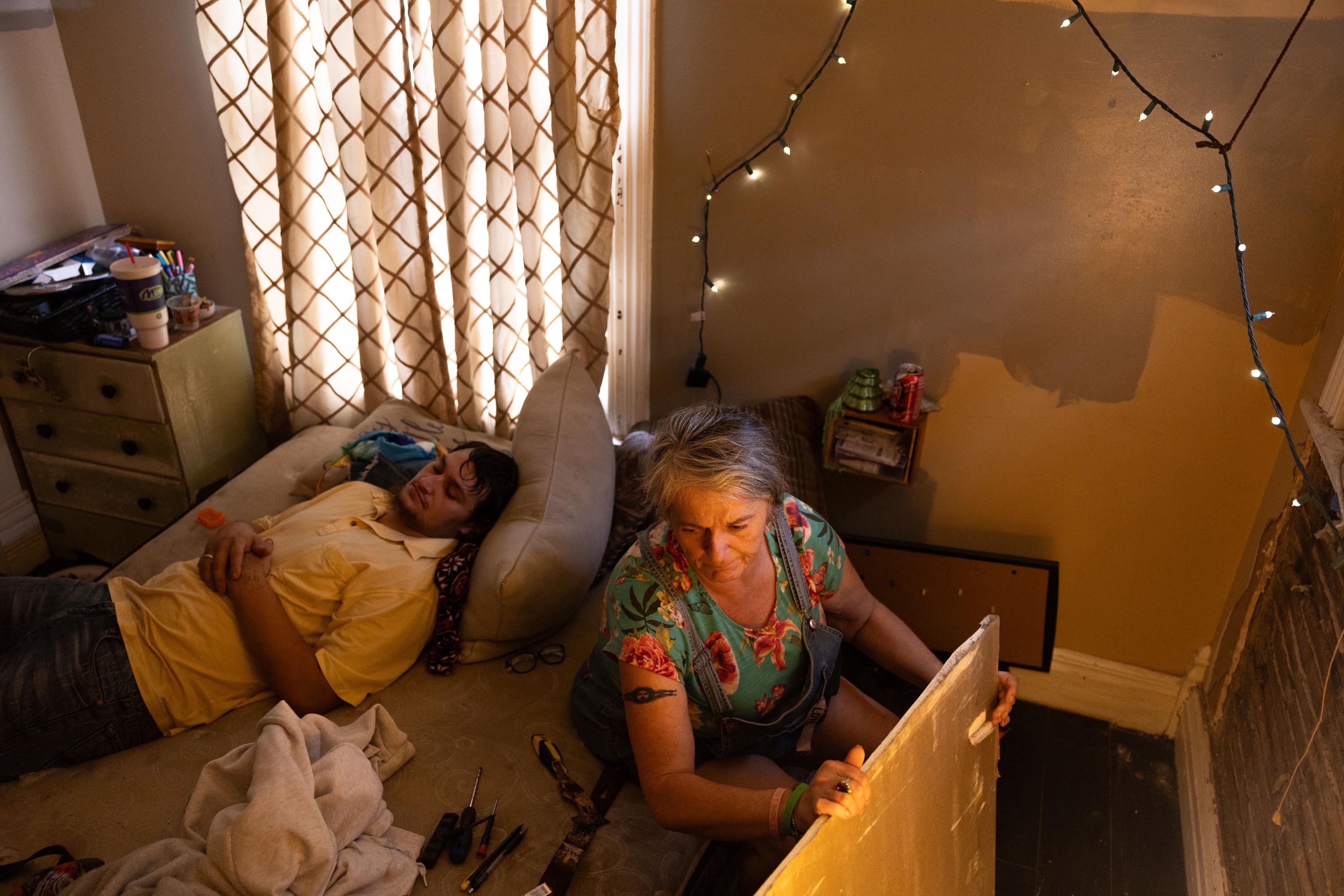 Carrie, Keeper of the House - Carrie Kuhl hangs mold-resistant drywall that she found...