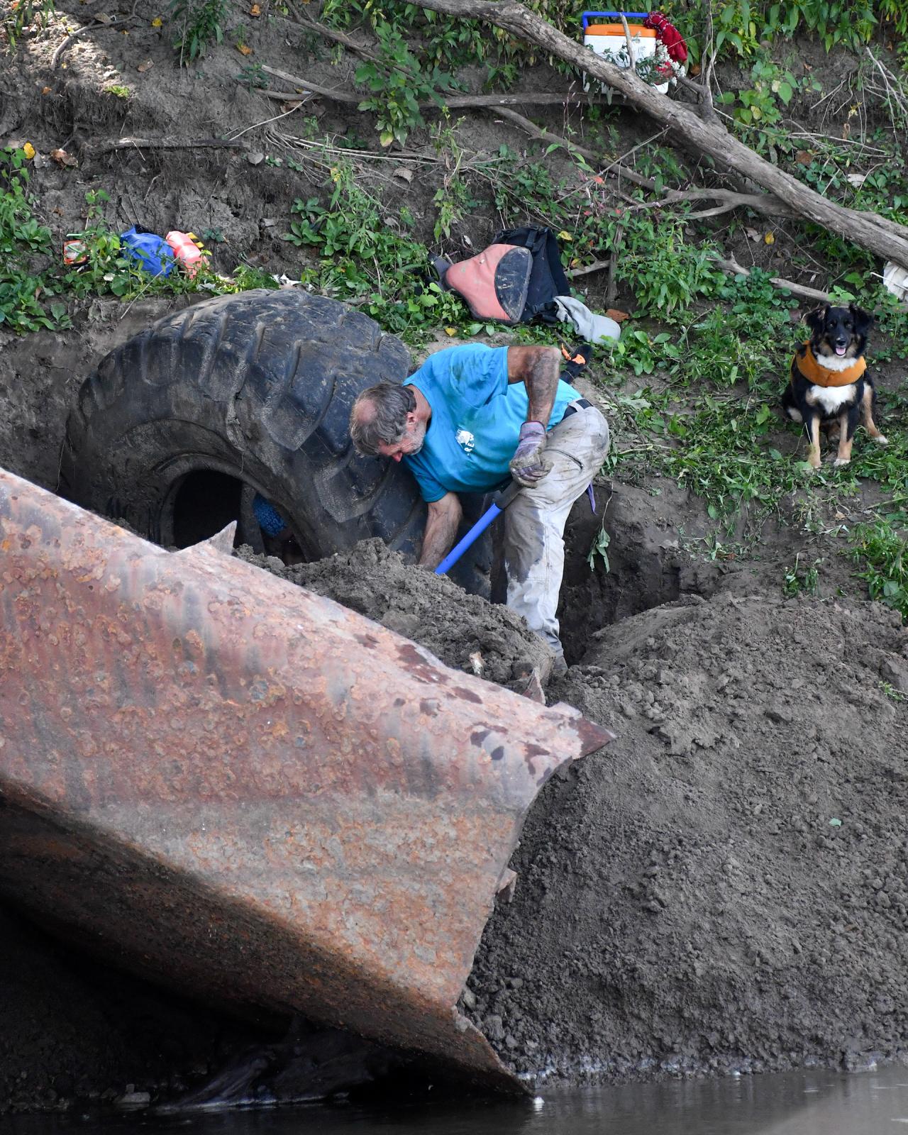 River Relief - Steve Olson digs up a large tire alongside his dog,...