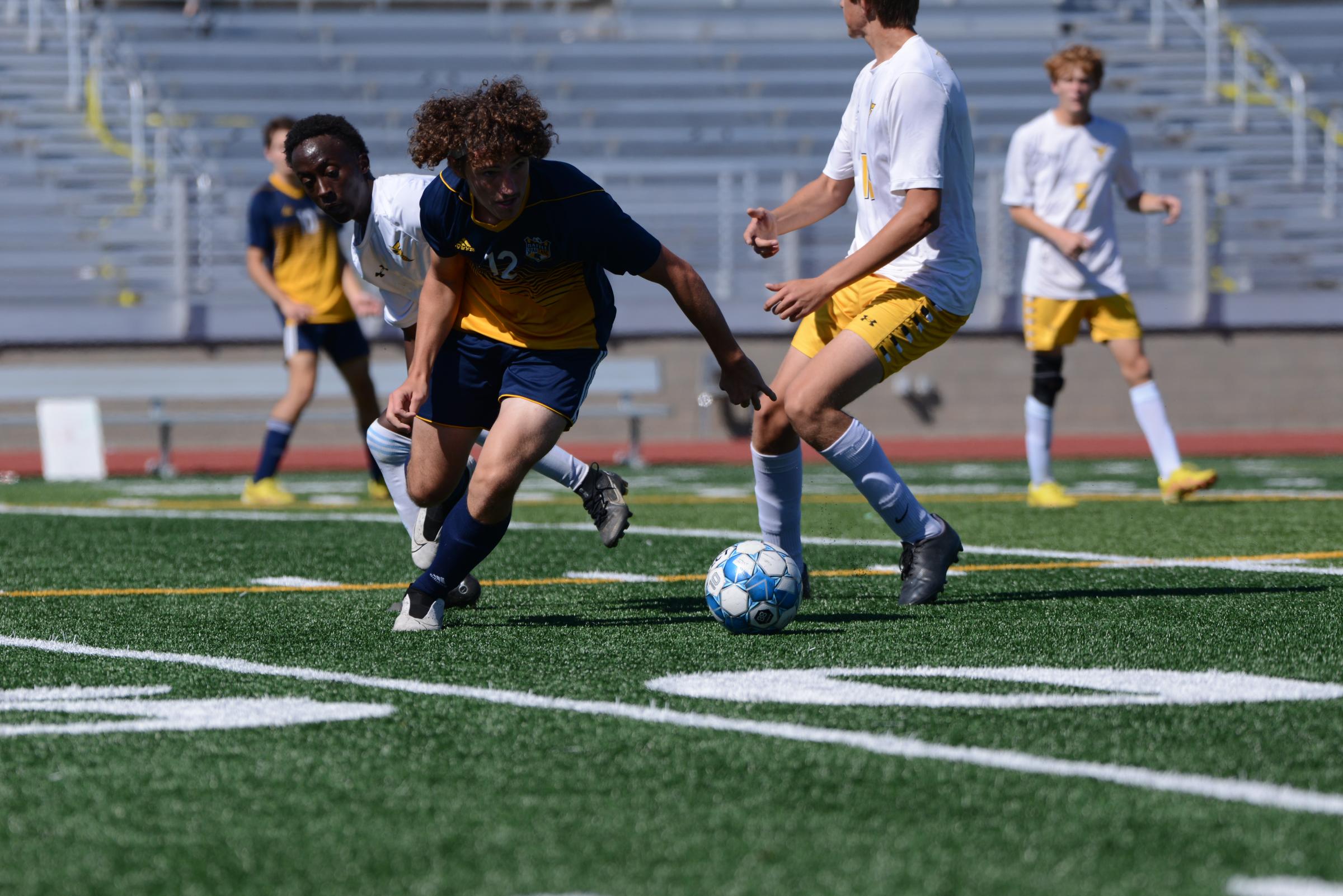 Battle junior C.J. McGuire kicks the ball past two Fulton defenders at the high school boys soccer game on Saturday, Oct. 1, 2022 at Muriel Battle...