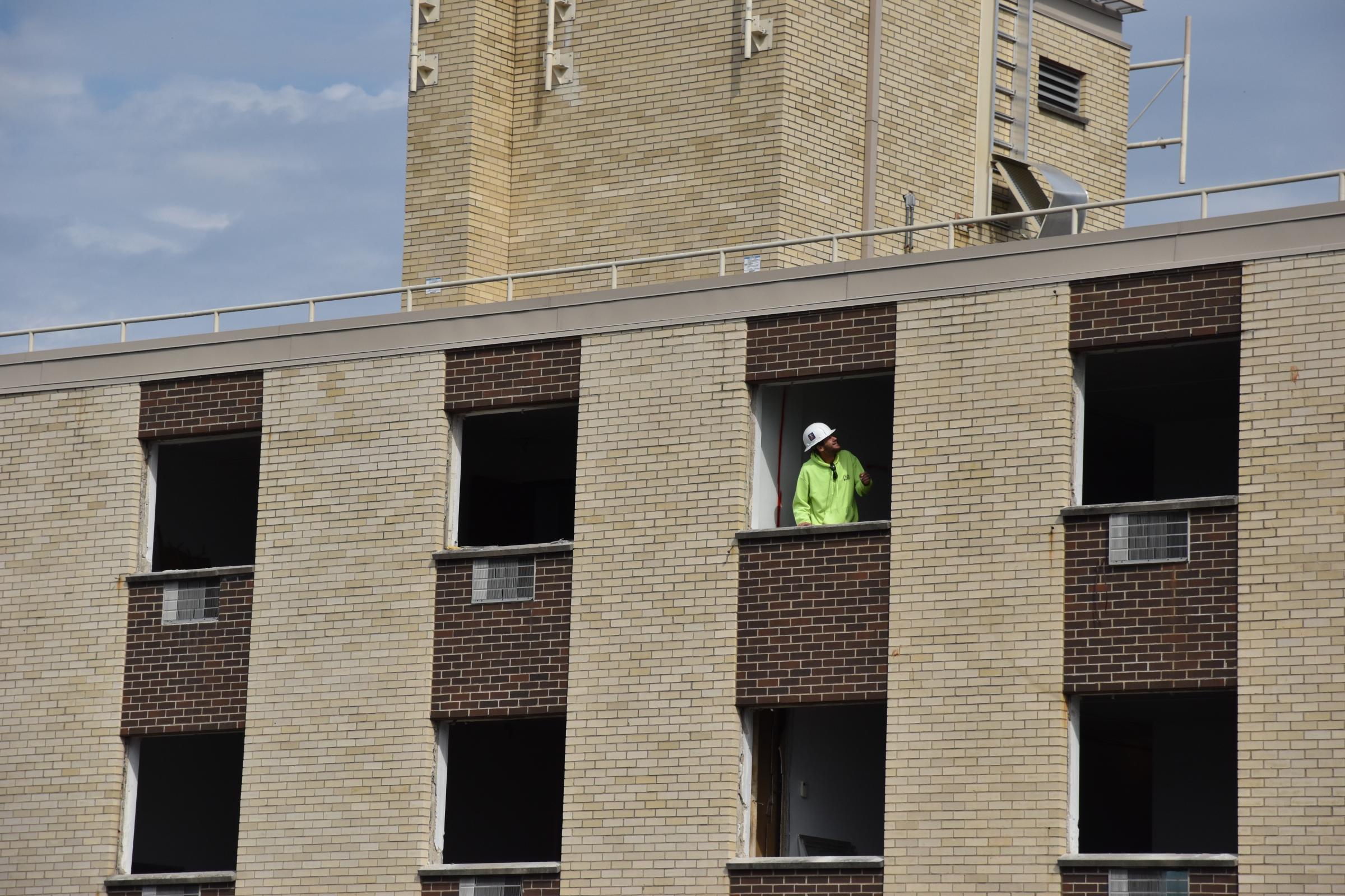 Photojournalism - A construction crew member peers out a window at Manor...