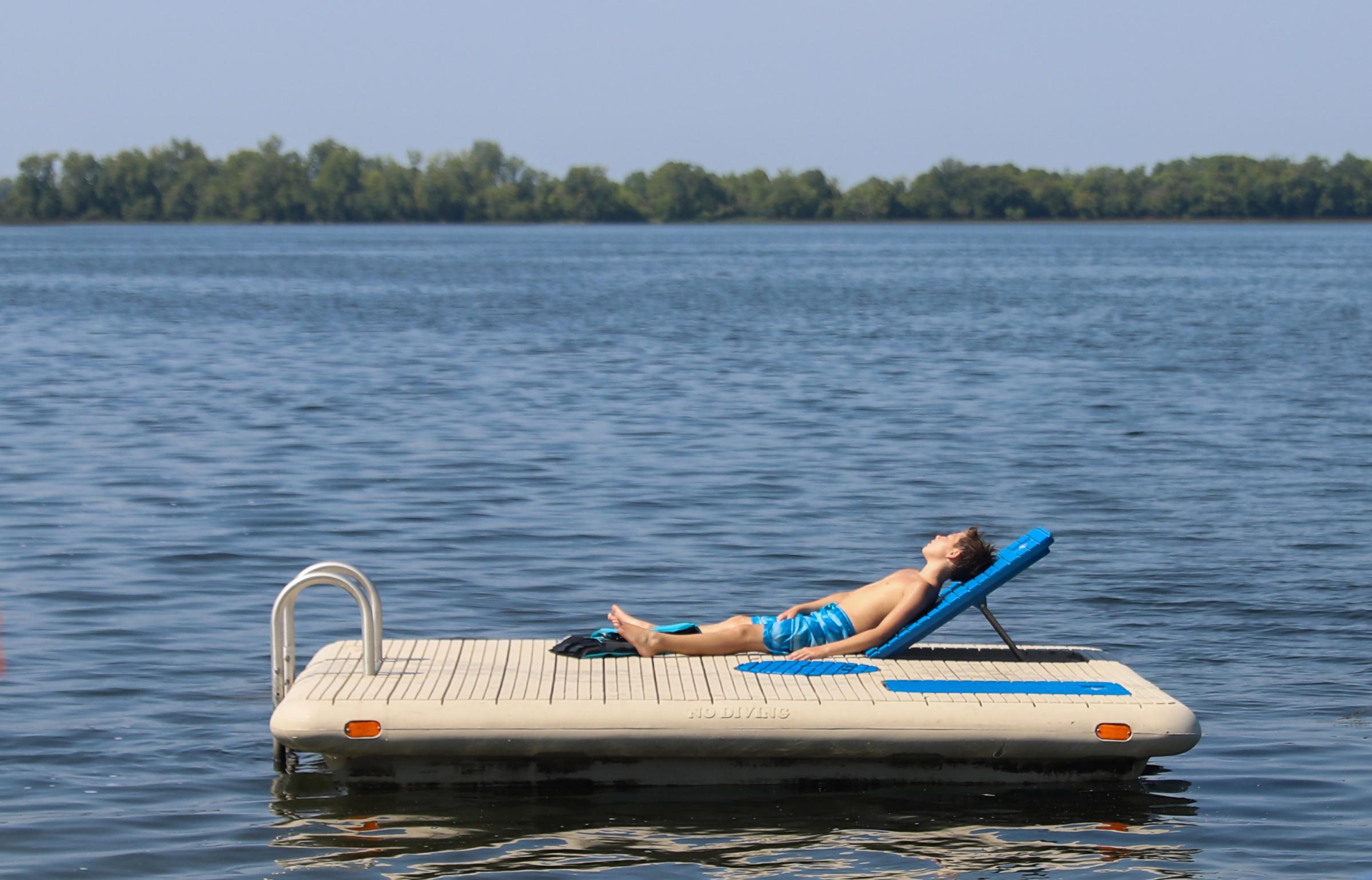 Singles - Elliot Pinkham, 9, sunbathes on a dock on Saturday Aug....