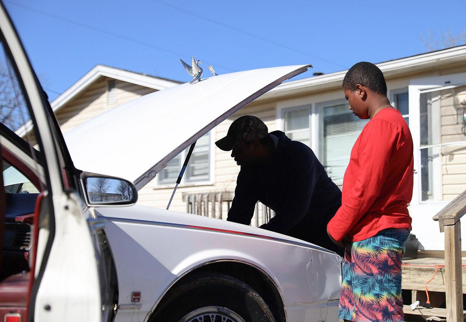 Inequity and Disrepair - Trinston Jones, left, works on a car with his son Zavion,...