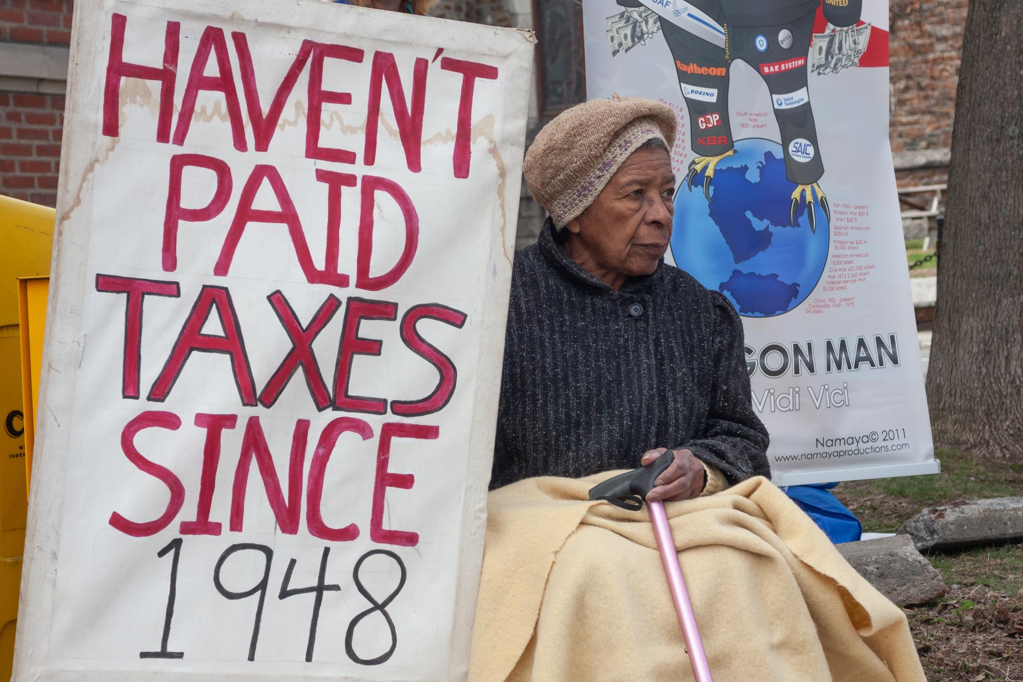Juanita Nelson sits with a sign outside of the Main Street Post Office in Brattleboro, Vt., on...