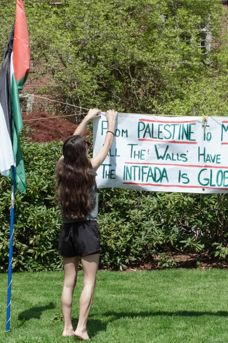 A student fixes a banner on Tri...College&rsquo;s encampment.