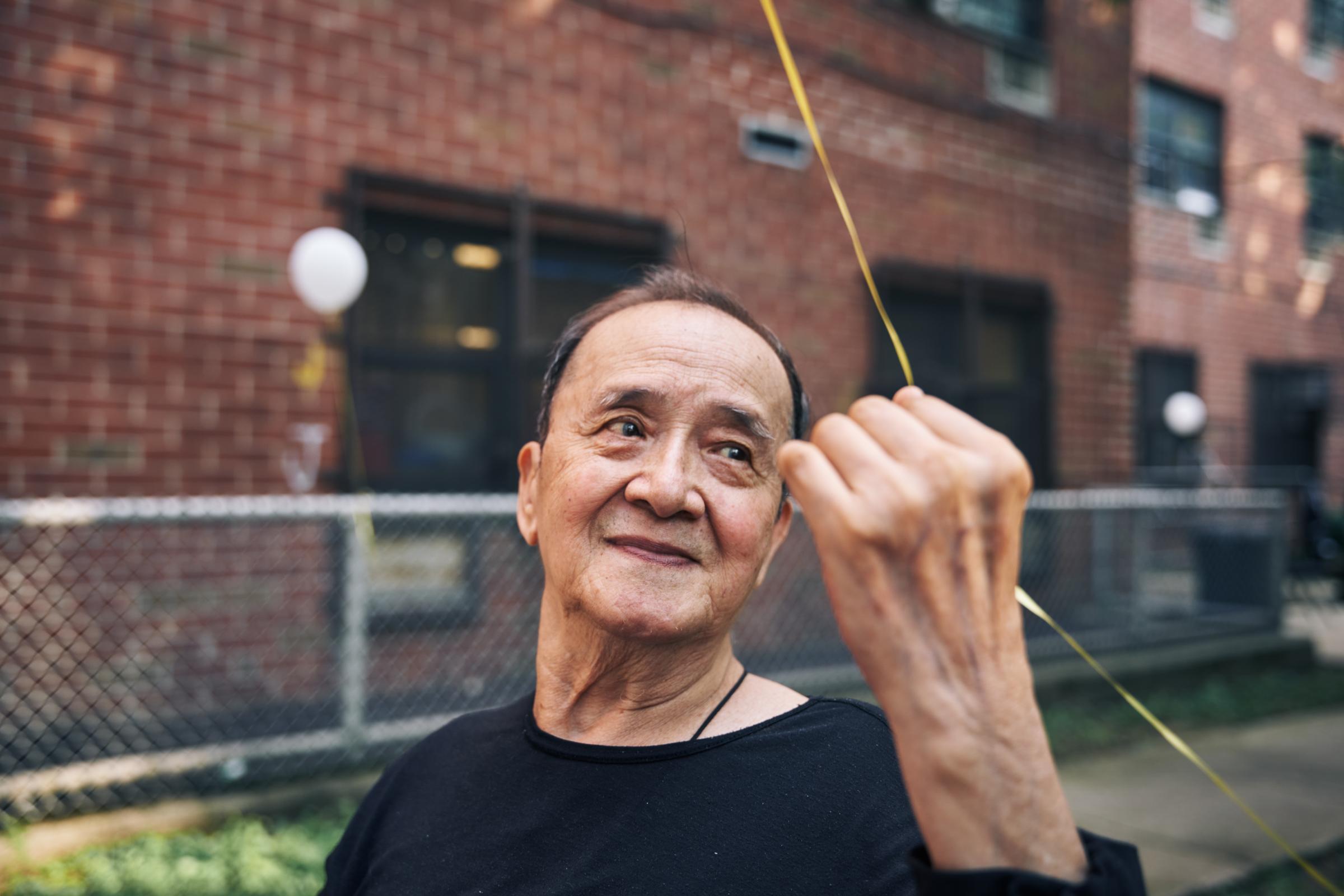 East Harlem - Henry Jian pulled a balloon tied to the bench in the...