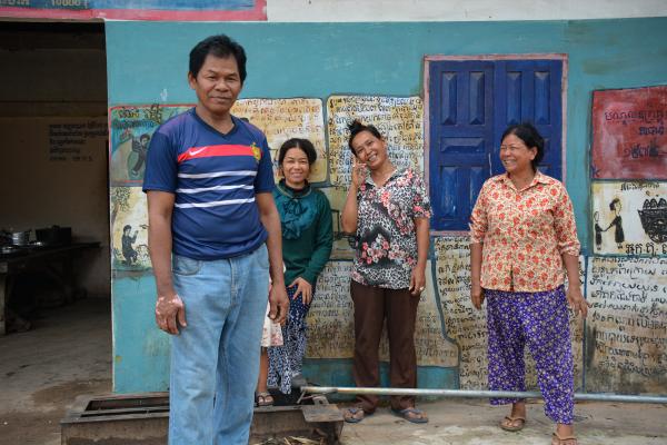 Image from Revisiting Khmer Rouge - Villagers stand in front of murals that document the...