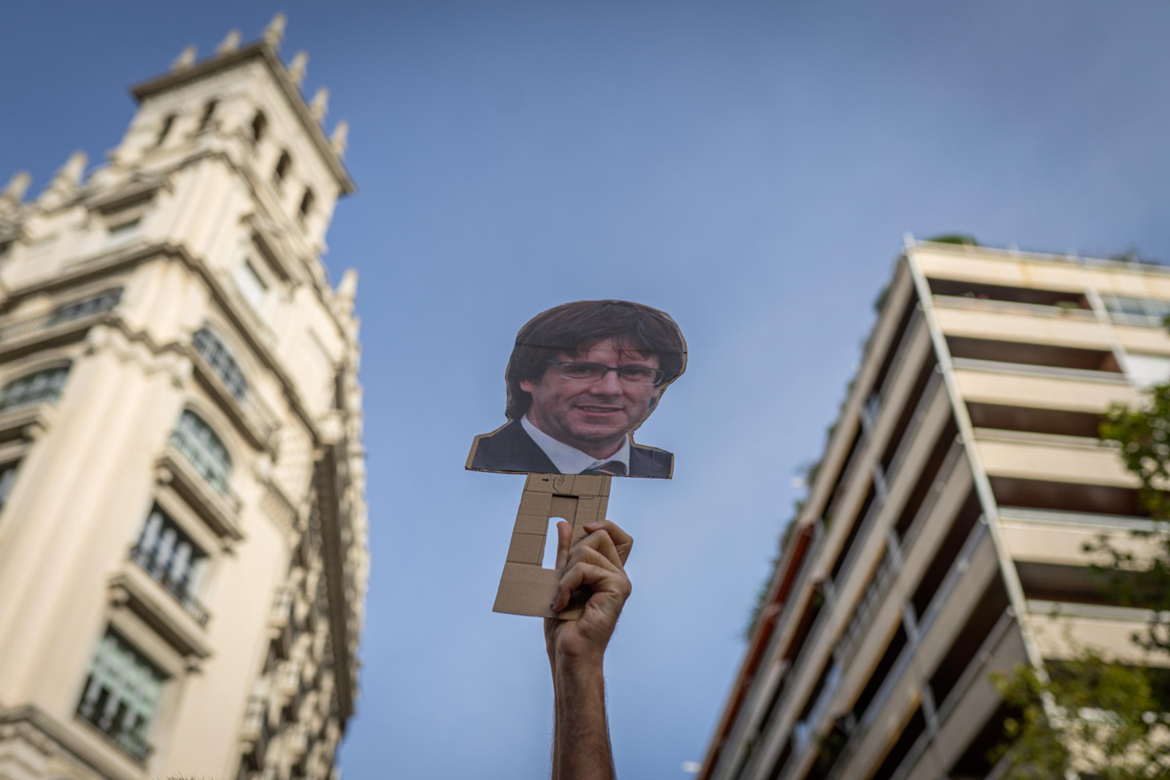 Daily news - A protester raises a mask with Puigdemont's face on...