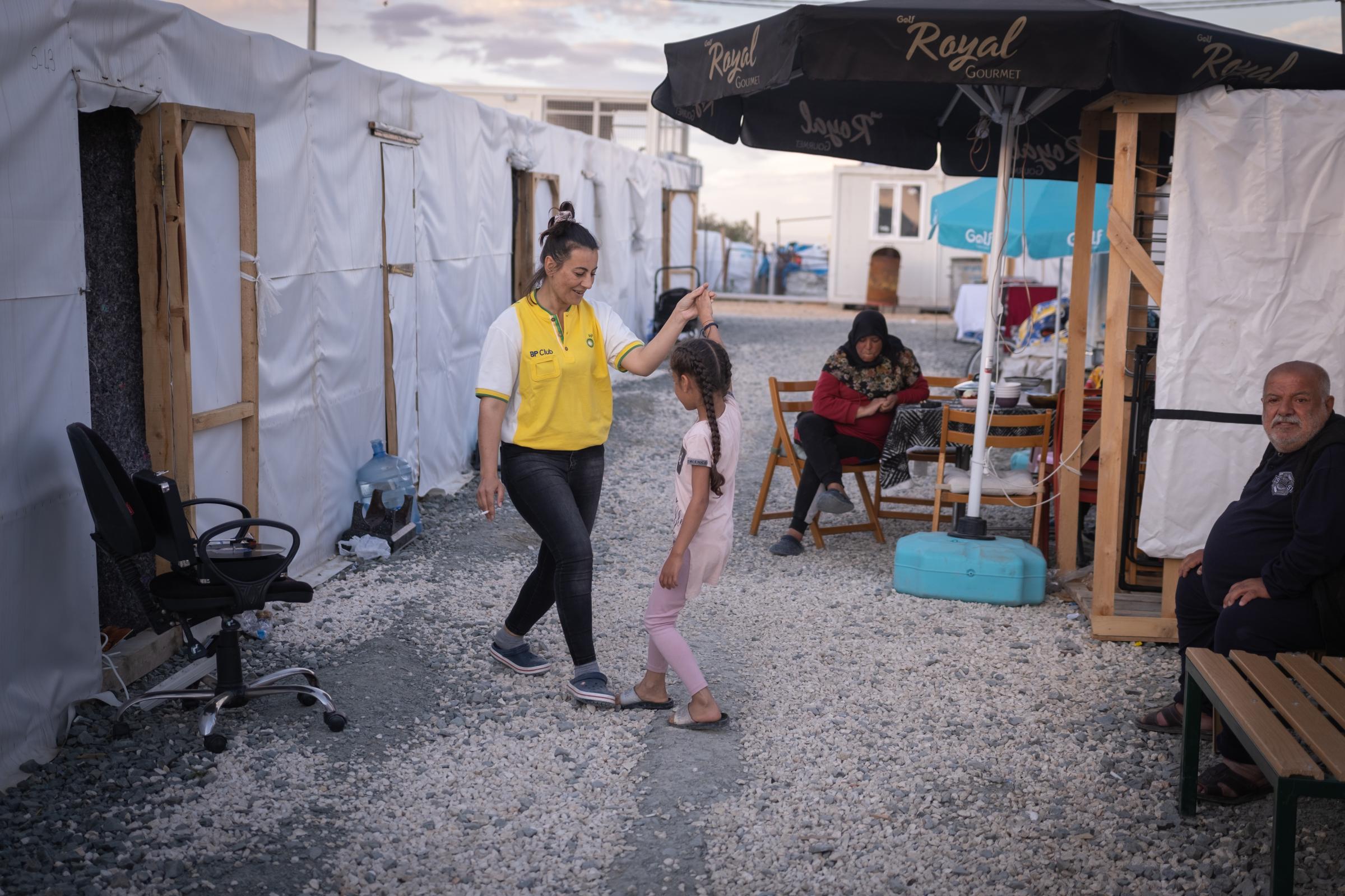One year on, the ancient city of Antakya struggles to show its first signs of life - Woman dancing with her relative in a tent camp in April 2023.