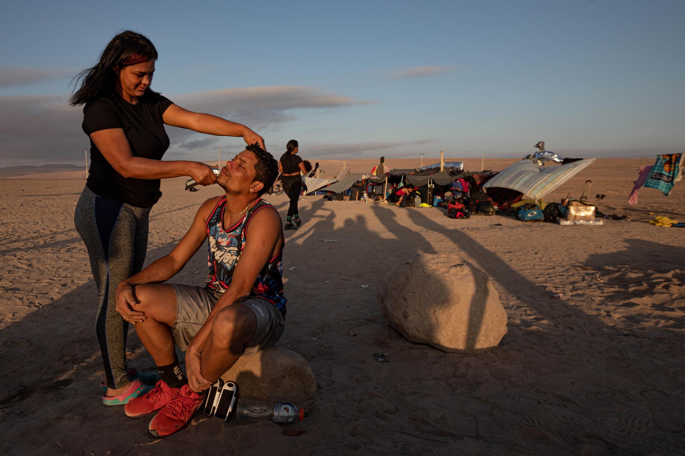 Fear, cold and xenophobia: broken dreams on the Chilean border - Yuri Gil, a stylist, is a Venezuelan migrant who cuts another migrant&#39;s beard. Migrants...