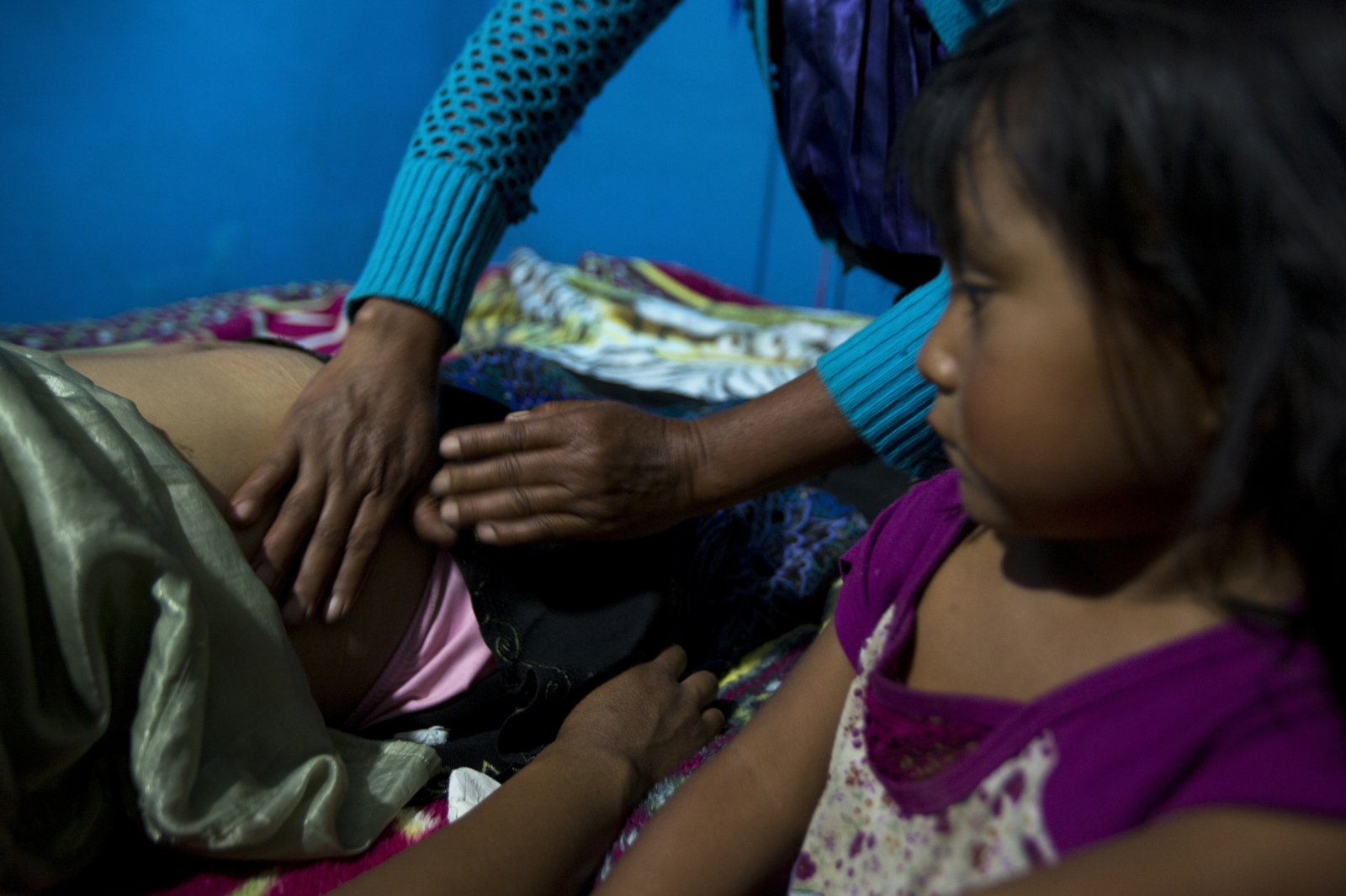  A young girl watches while traditional midwife MarÃ­a LÃ³pez Gonzalez, otherwise known as â€œDoÃ±a Mari, massages the abdomen of the girlâ€™s...