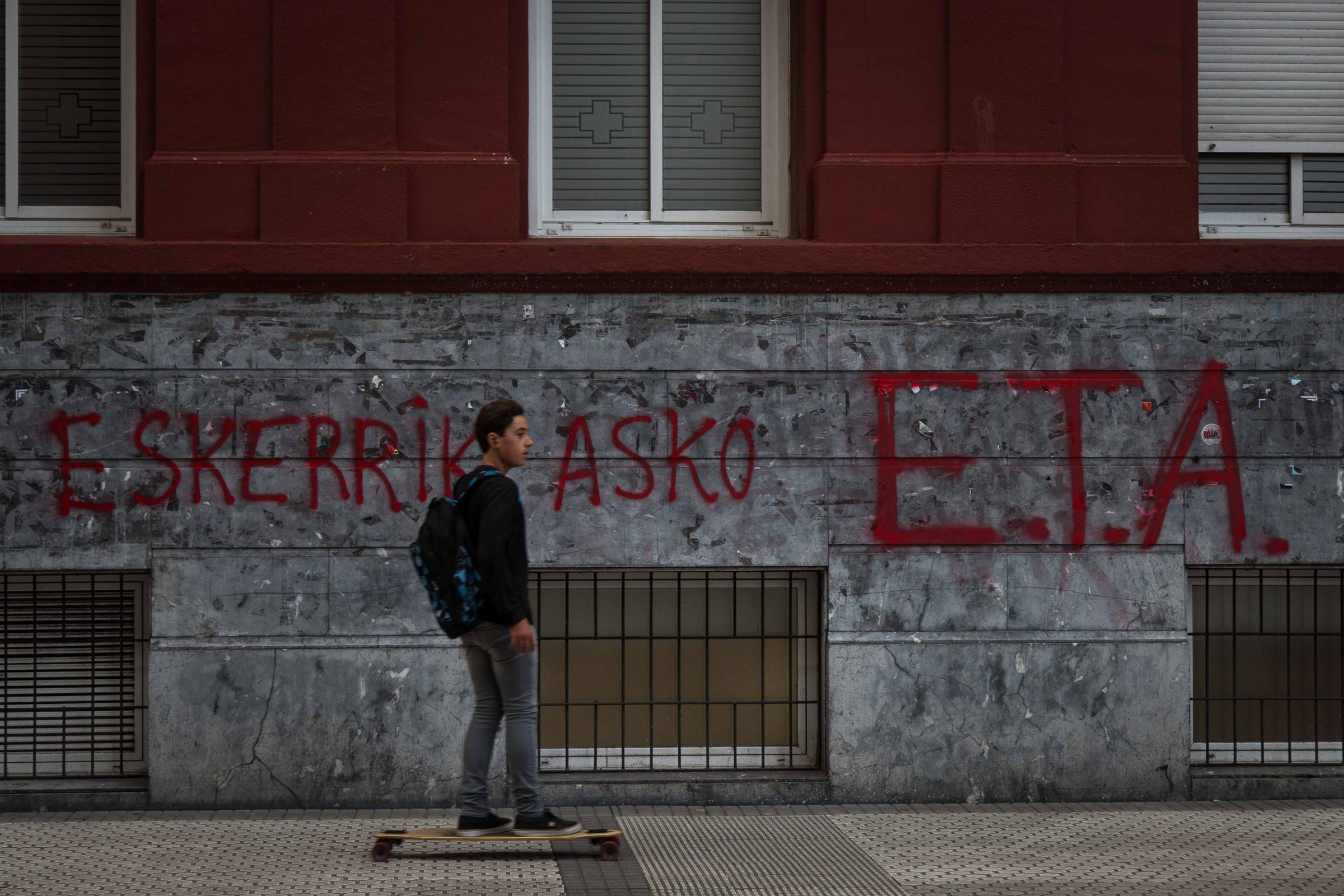 Basque Country - A young man on a skateboard passes by a graffiti reading &quot;Eskerrik asko, ETA&quot;...
