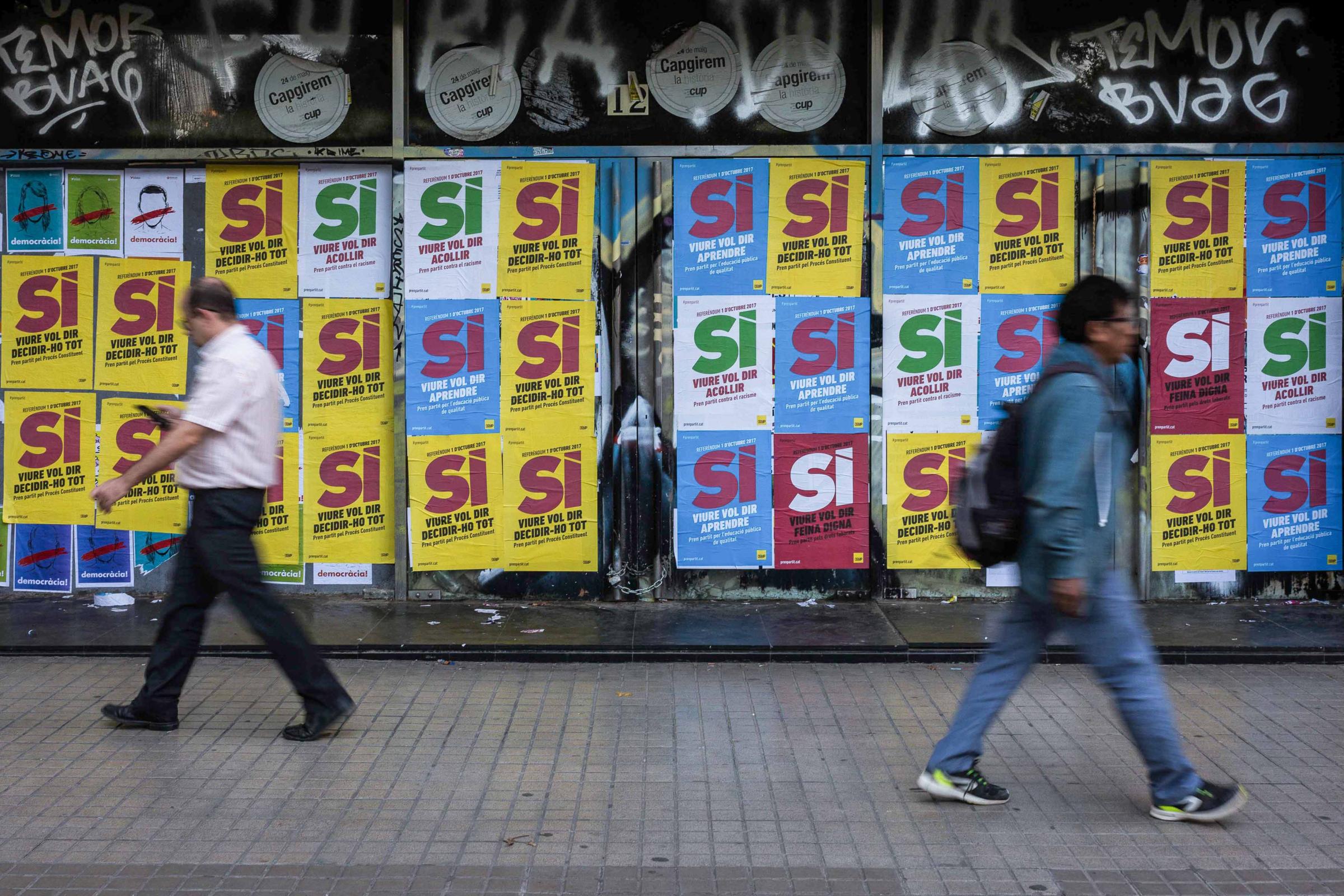 September 29th, 2017. Barcelona, Spain. Two people walk through the center of Barcelona with posters calling for a YES vote for the referendum, in...