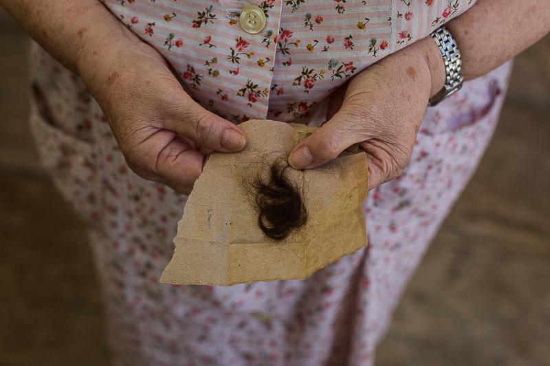 the end of oblivion - A woman shows a lock of hair from one of her relatives....
