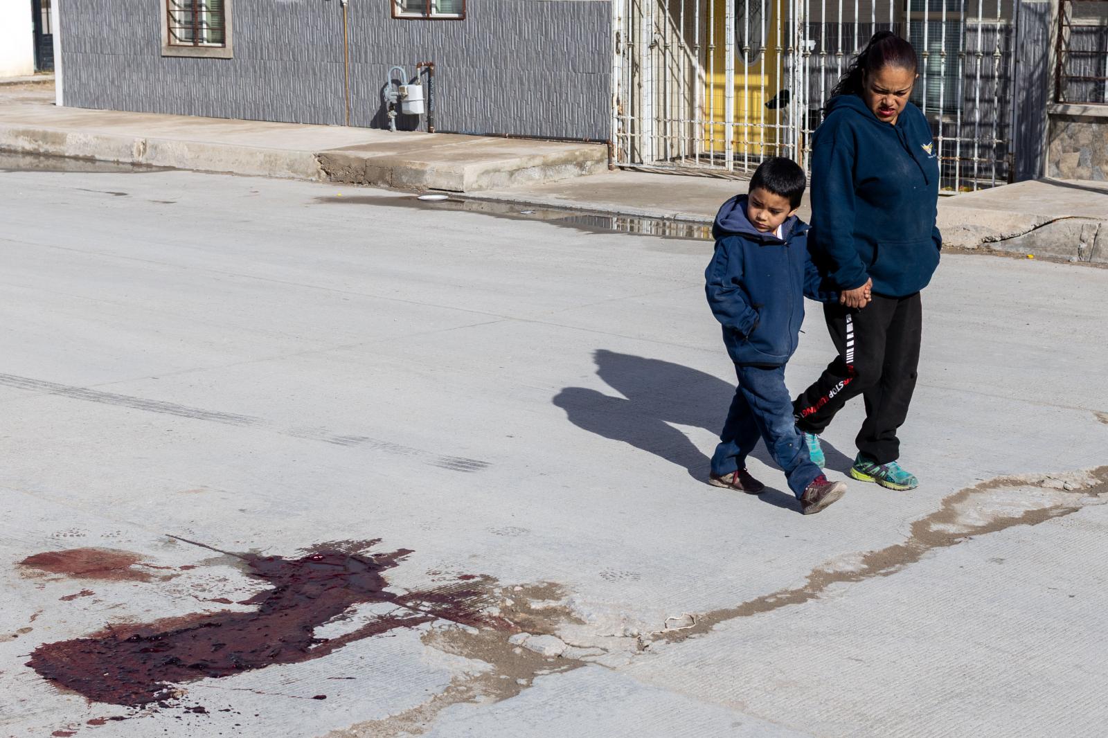  A woman and her son walk past ... amid visible traces of death. 
