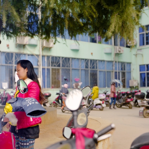 A woman waits in the parking lot of a small city hospital in the Jiangxi province in China.