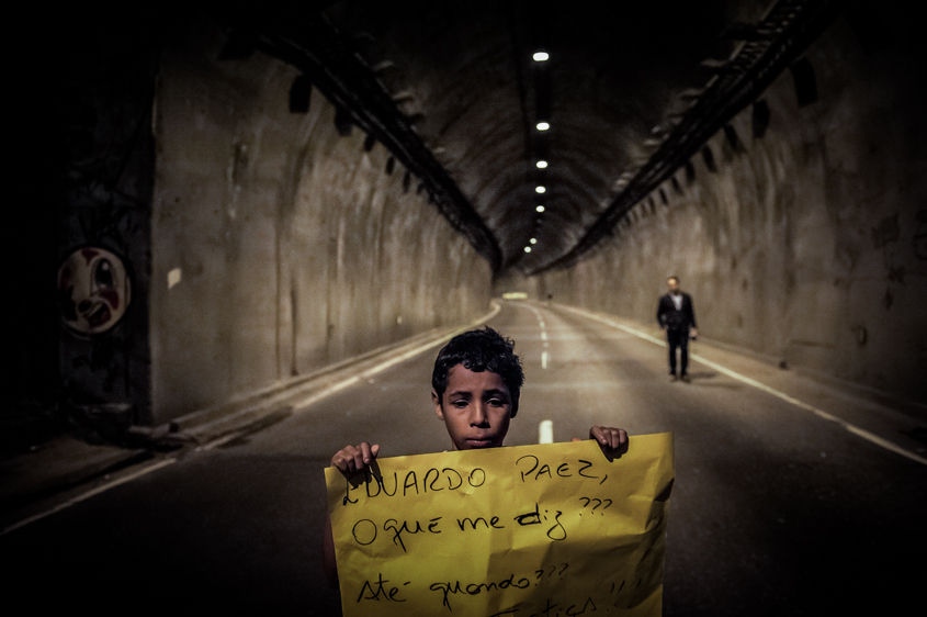     A boy holds a sign in front of a blocked tunnel during a protest to press for clarifications on missing persons including a bricklayer who recently disappeared, in Rio de Janeiro, Brazil, Thursday, Aug. 1, 2013. The 42-year-old father of six was picked up for police questioning on suspicions of involvement in drug trafficking, but was released shortly thereafter. He has not been seen from since. Official statistics showing that nearly 35,000 people were reported as missing in Rio state alone over the past five years.    