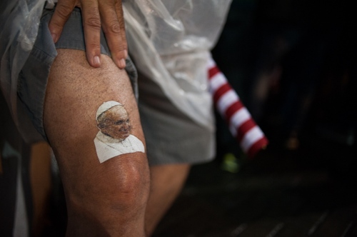      A man holds up the cuff of his shorts to show off his temporary tattoo of Pope Francis while waiting to get a glimpse of the pontiff making his way to the St. Francis of Assisi of the Providence of God Hospital, where the Franciscans look after alcohol and drug addicts, in Rio de Janeiro, Brazil, Wednesday, July 24, 2013.     