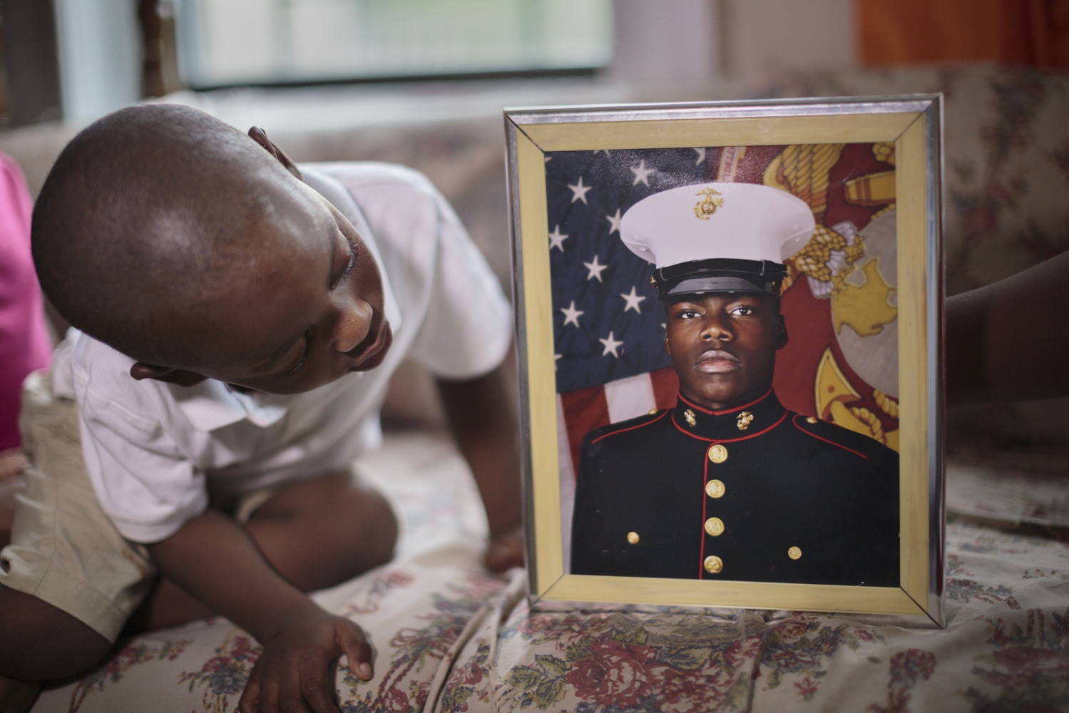  Didier Mejia looks at his cousinâ€™s military photograph. Many immigrants join the U.S. military...
