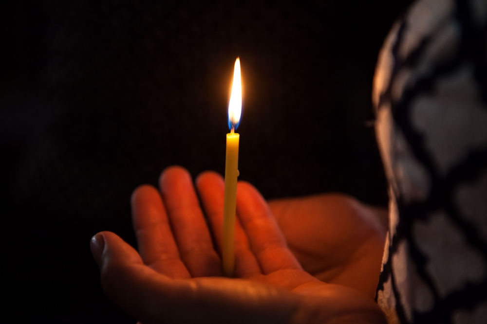 Woman holds a lite candle at an orthodox church in Moldova