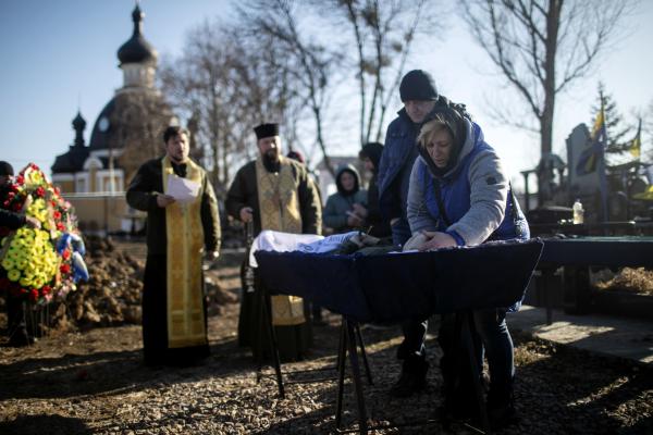 The parents of Yuri (23), a soldier who died fighting Russian forces near Kyiv, mourn over his body during the funeral.