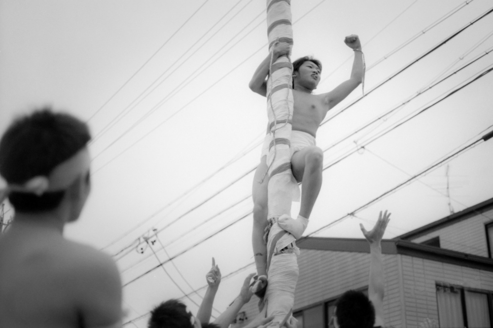 Man climbs wrapped bamboo at the Japanese Spring festivals